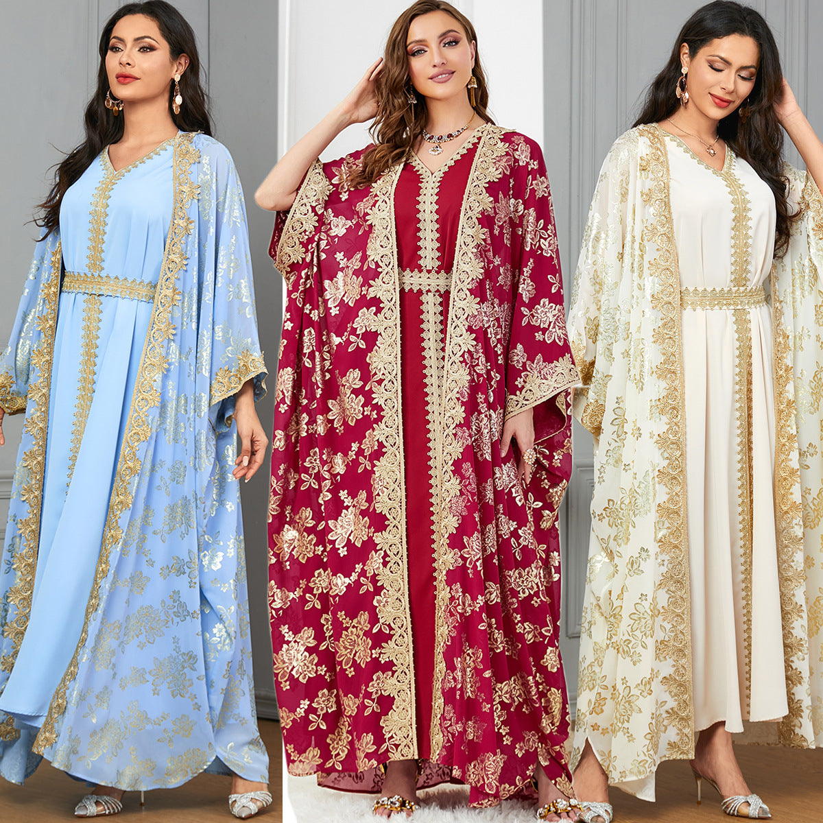 Three women wearing embroidered kaftans in blue, red, and white.